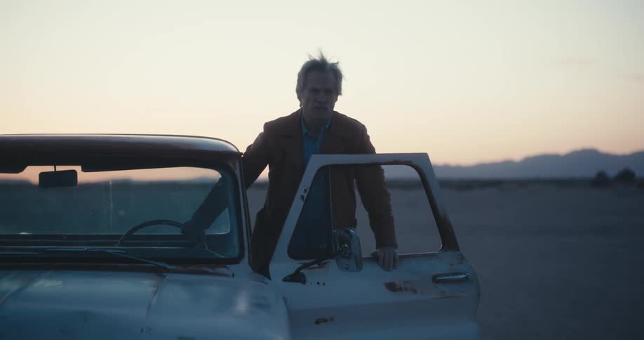 A man is getting into his car in a rural area