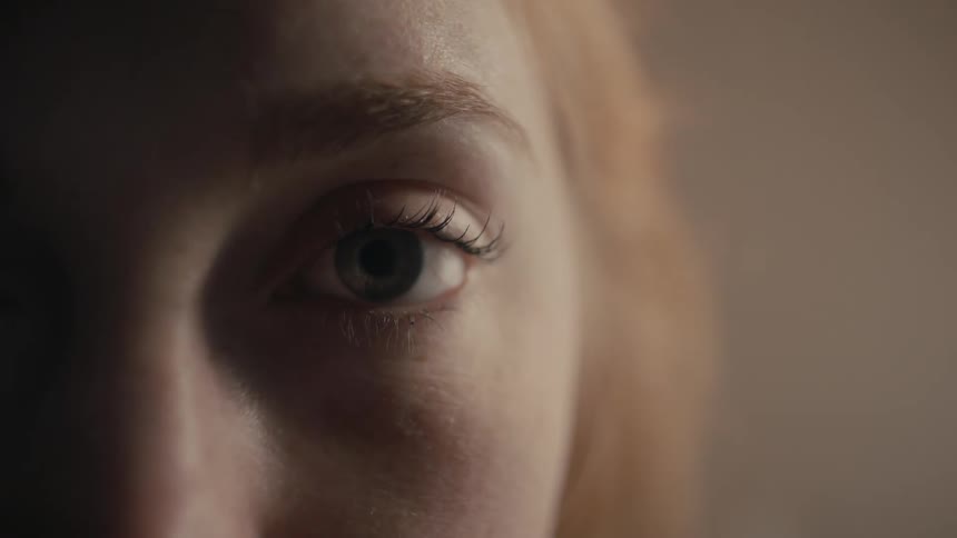 A woman with red hair opens her eyes