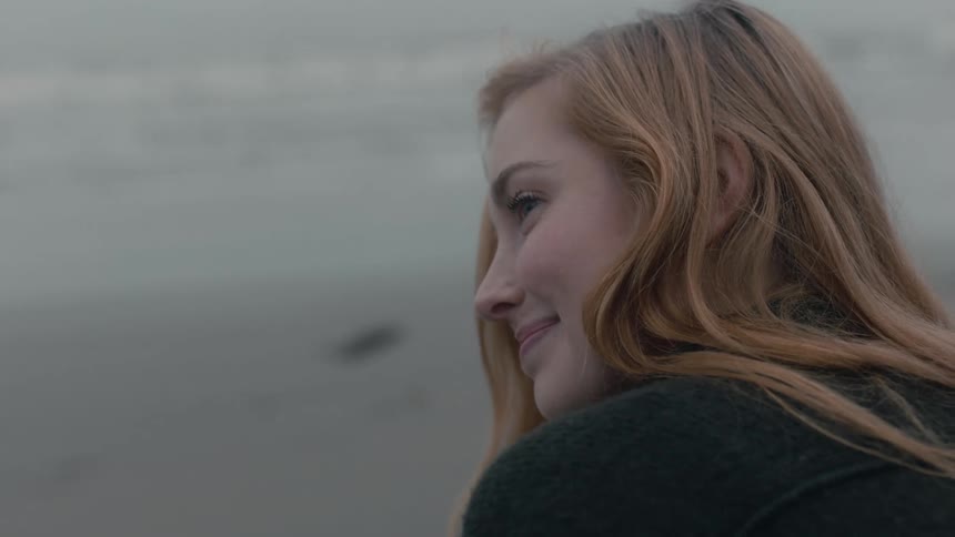 A woman is smiling by the beach during the day