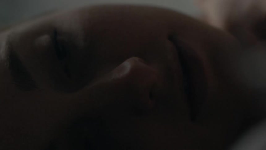 A woman is on her back in bed looking around