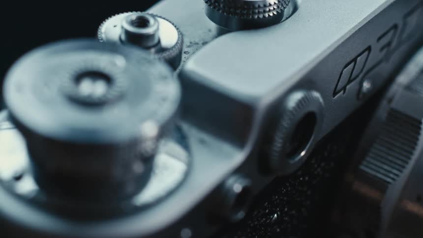Silver and black camera has model number and multiple settings labeled with numbers