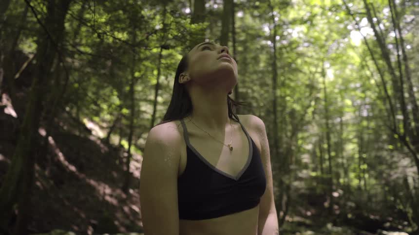 Young fit woman looks up meditatively in a grove on the forest
