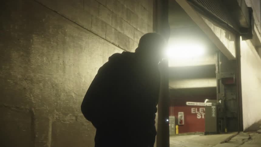 A man walks down a sidewalk past a parking garage