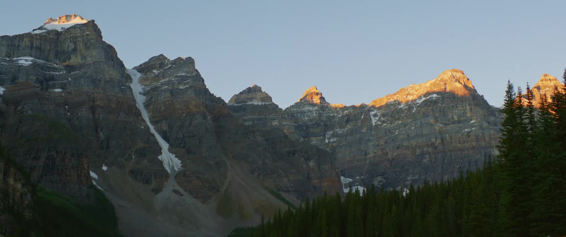Bright sunlight makes the peaks of mountain tops glow orange
