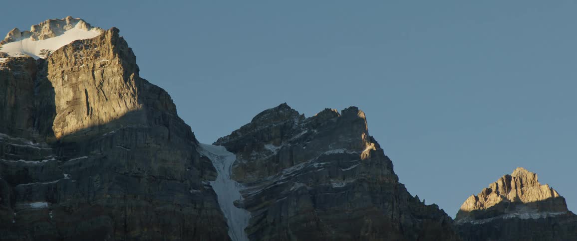 Rugged mountain peaks with snow against clear blue sky