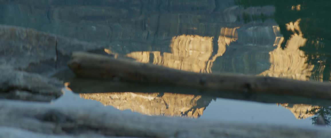 Water rippling with a reflection of a mountain range trees and the sky
