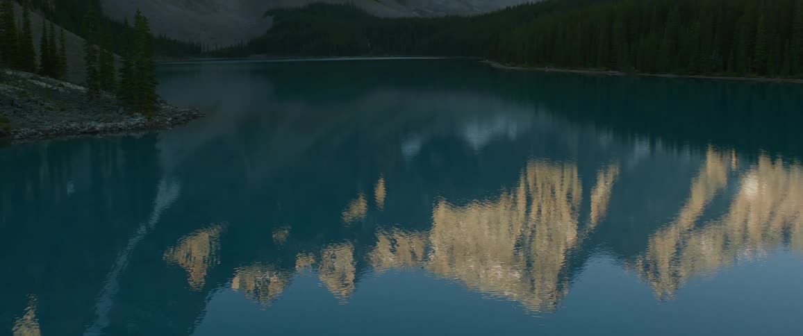 Peaks of a mountain range reflecting in the placid waters of a lake
