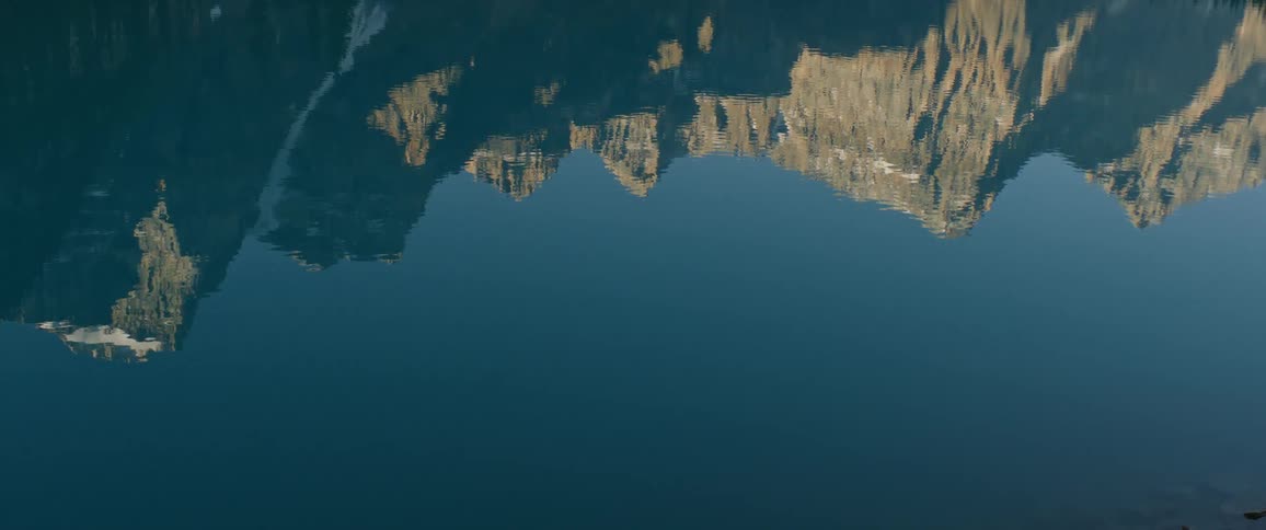 Peaks of a mountain range reflecting on the calm waters of a lake