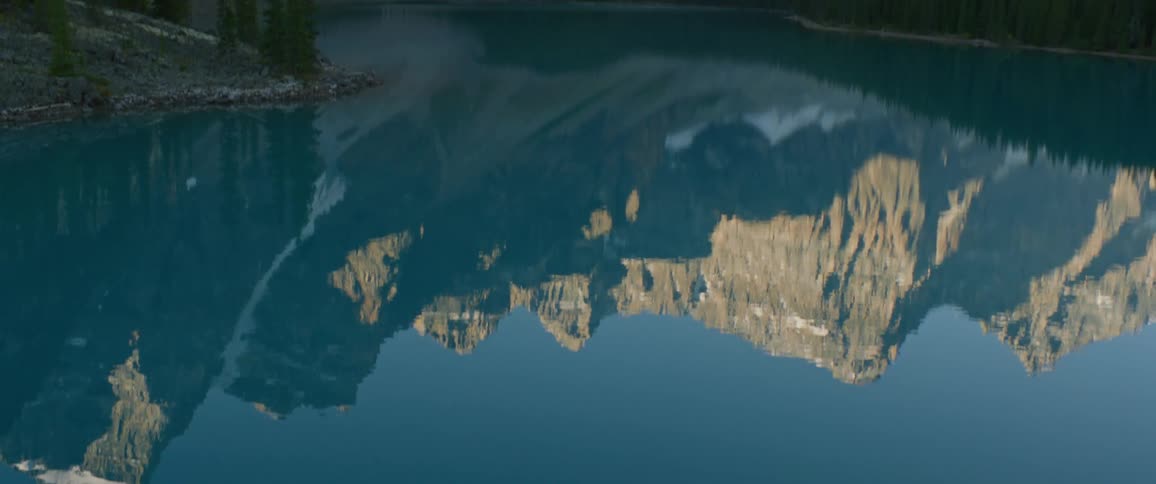 A mountain landscape is reflected in a rippling lake on a winter day
