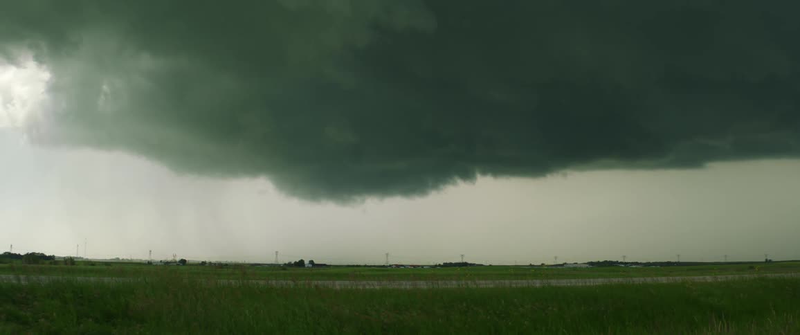 A truck travels along a country road as dark clouds loom overhead
