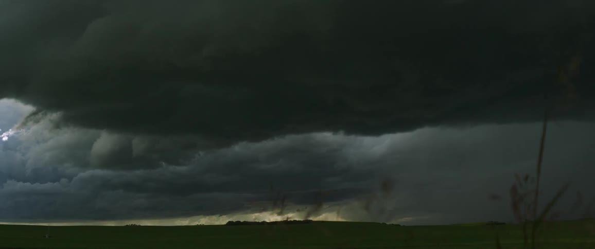Dark storm clouds blowing over a rural field in the wind