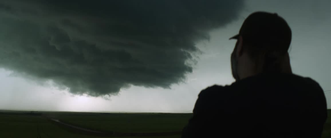 Man takes pictures of cloud formation hovering low over road running through countryside