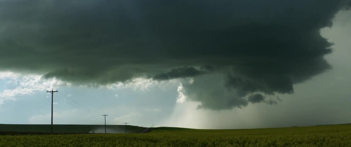 Storm clouds raining down on a rural field on a summer day