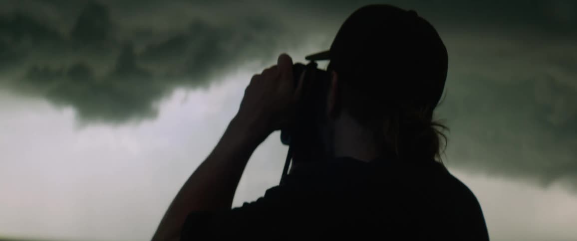 Man takes pictures of dark clouds in a field