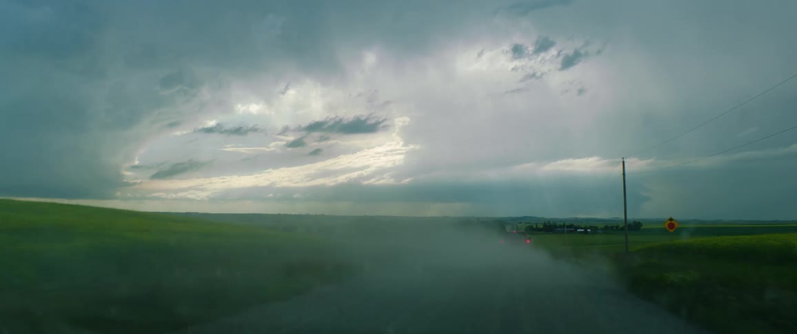 Truck drives down rural road at dusk leaving a trail of smoke behind it