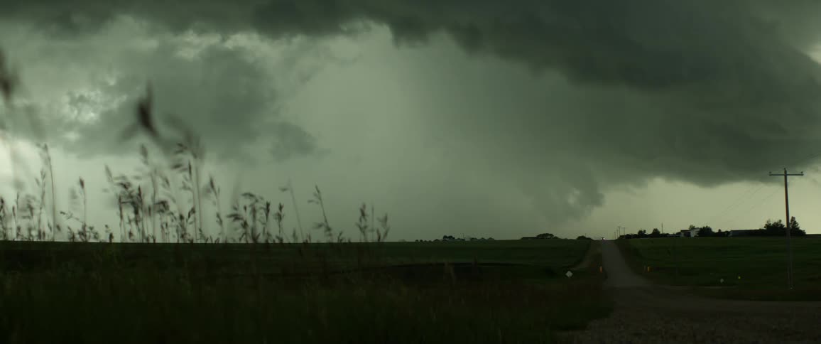 Dark storm clouds floating over a rural field on a windy day