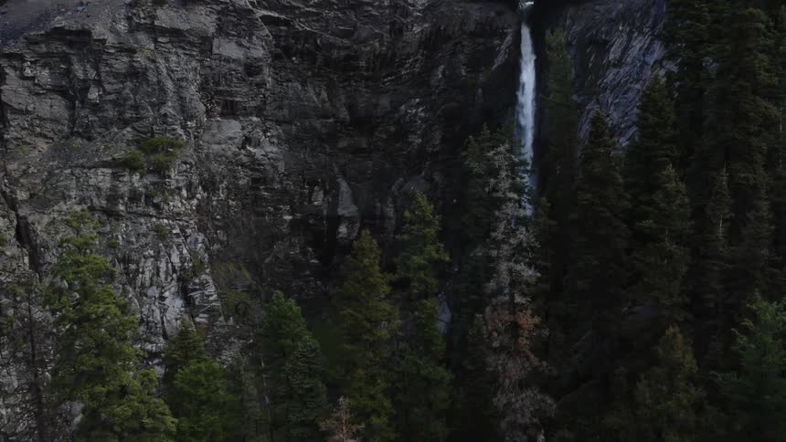 A waterfall flowing over a large rocky cliff in a forest