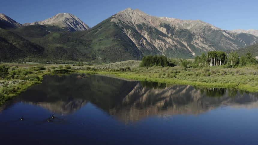 Mountain range reflecting on the calm waters of a lake on a clear day