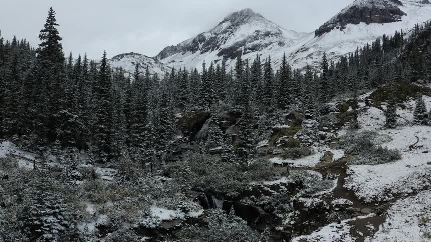 Exterior view of mountains and trees with light snow on the ground