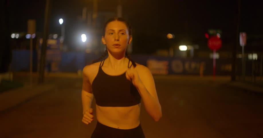 A woman is jogging in a city at night