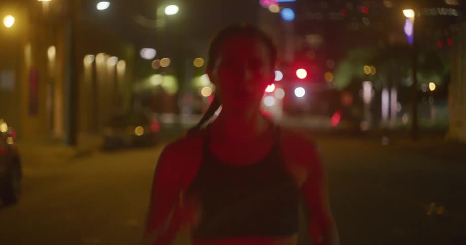Young fit woman wearing sports clothing jogs in the city streets at night