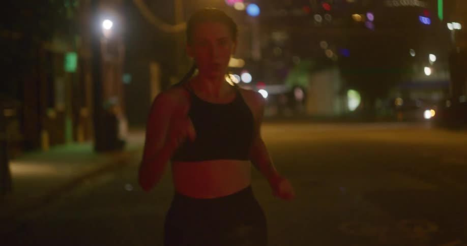 Young fit woman wearing sports clothes jogs on the city streets at night