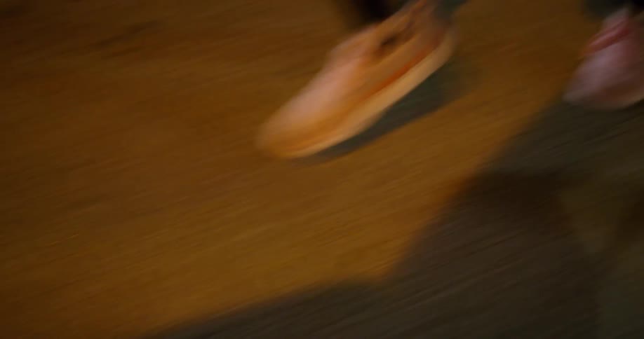Woman wearing a black exercising outfit and brown shoes is running down the street
