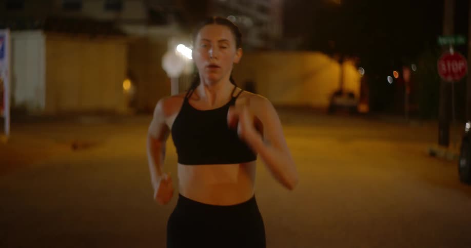 A woman is running down the middle of the street at night