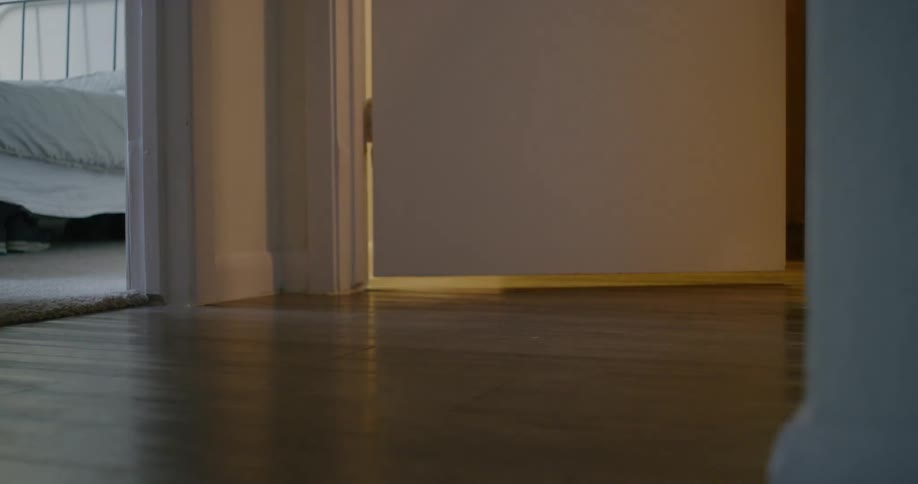 A woman walks in to a room in a home and closes the door