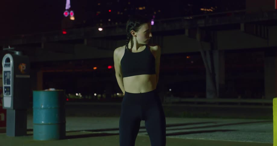 Woman stretching outside near the city at night