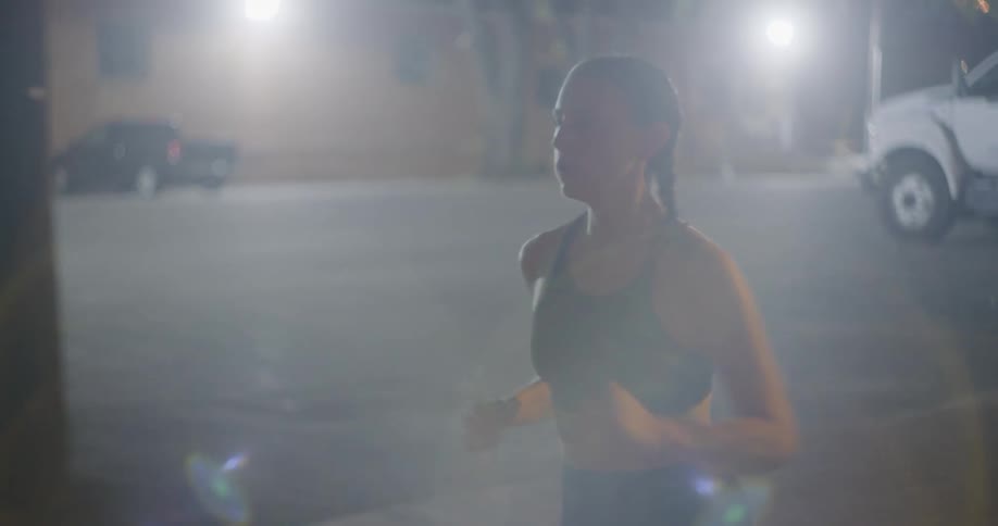 A woman is jogging through a city at night
