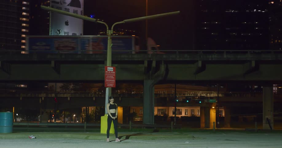 A woman stands on a city street and stretches