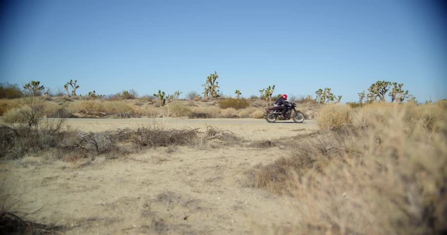 Motorcycle rides by at full speed on a road through the desert
