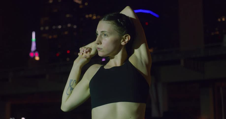 Woman stretching outside at night in a city