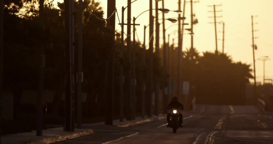 A person is riding a motorcycle on a road at dusk