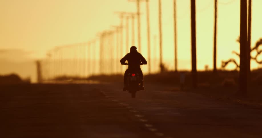 A person is driving a motorcycle at dusk