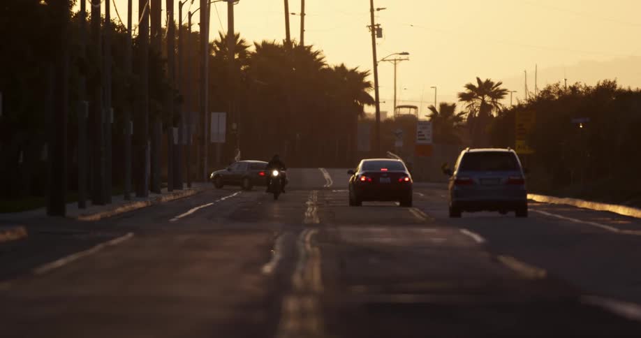 A motorcyclist drives along a street and passes several other vehicles