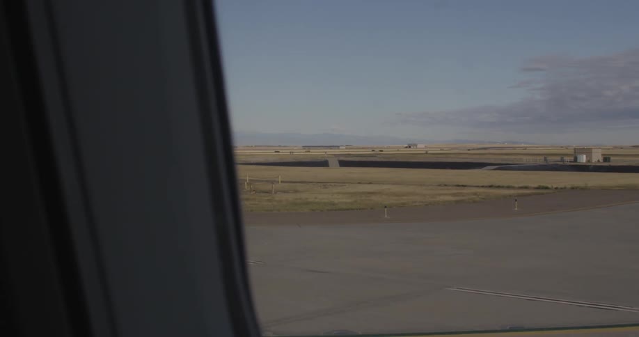 The runway of an airport is seen from a window as a plane taxis