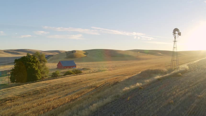 Skimming above a fallow field to reveal an idyllic farmstead surrounded by rolling hills