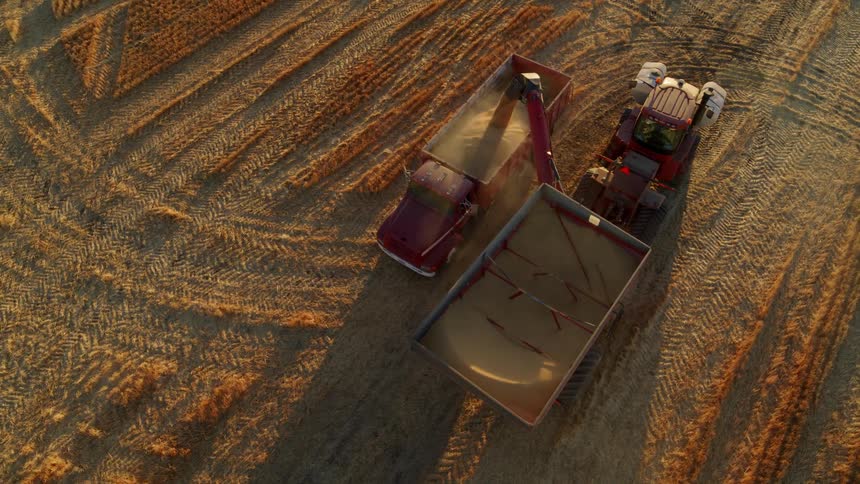 Subtle orbit around a tractor transferring harvested wheat into a grain truck for transport to a silo