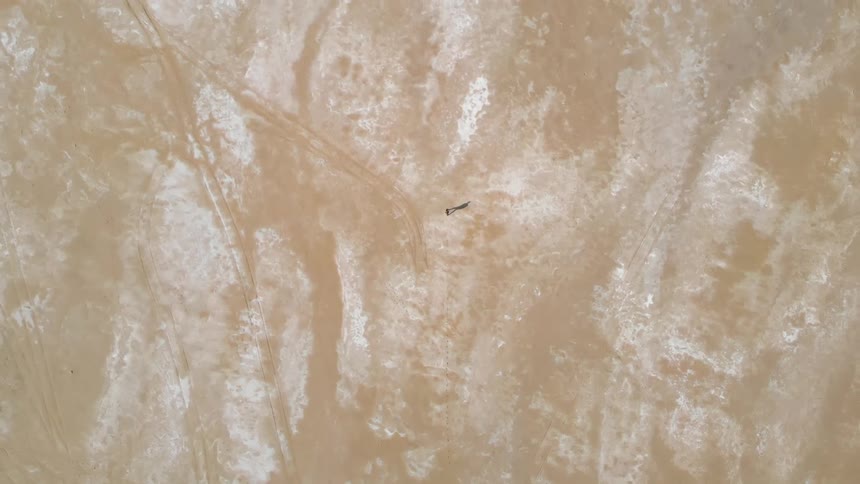 Flat shiny surface in tan and white with parallel tracks on one side