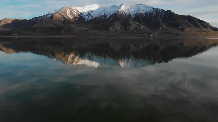 Water ripples in a large body of water in front of snowcapped mountains