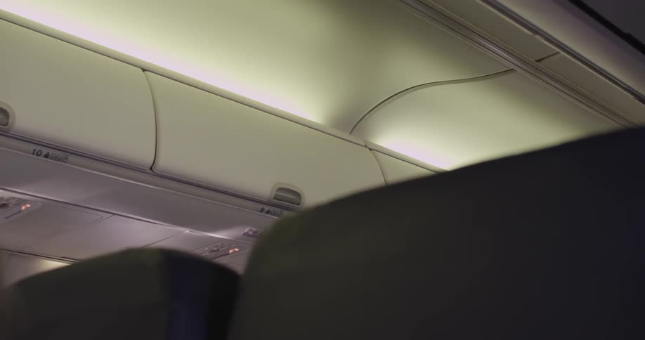 Carry on luggage compartment of an airplane is seen from a row of seats