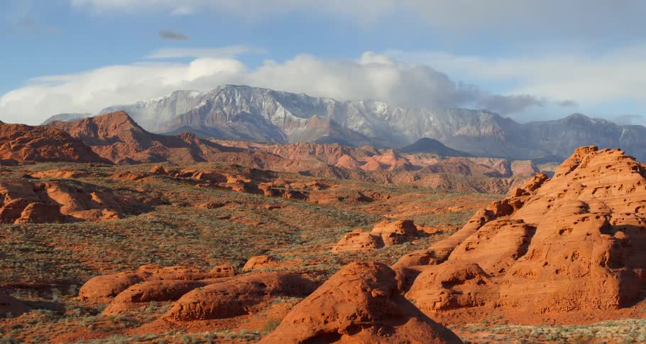 Red rock formations with snowy mountains in the distance in nature