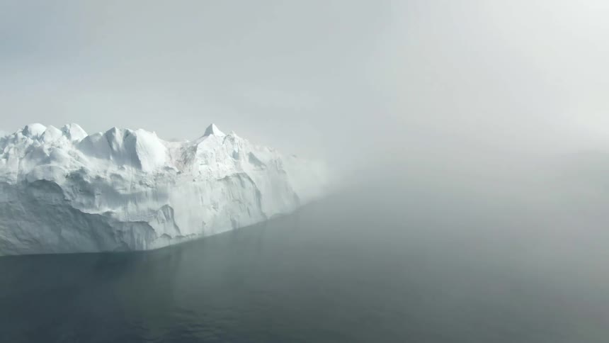 An aerial view of a large iceberg on a foggy day