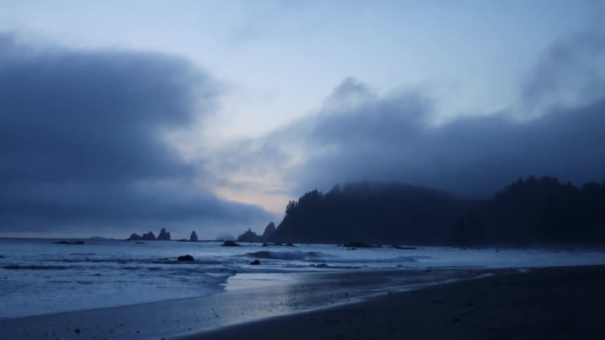 Beach with low tide and little sun with a blue hue and clouds