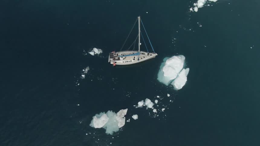 An aerial view of a boat in the ocean by an iceberg