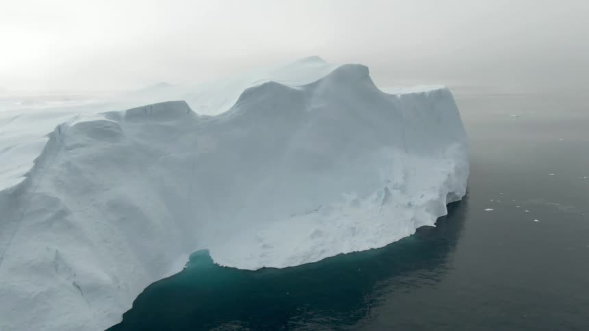 White ice iceberg floating on the calm ocean waters at sunset