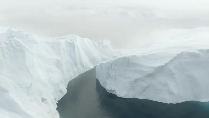 An aerial view of an arctic region with large icebergs on a cloudy day