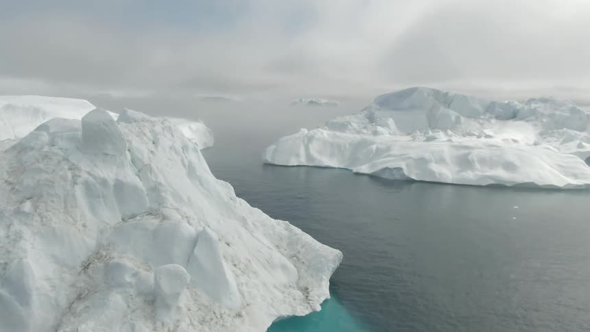 Icebergs float in the arctic ocean on a cloudy day